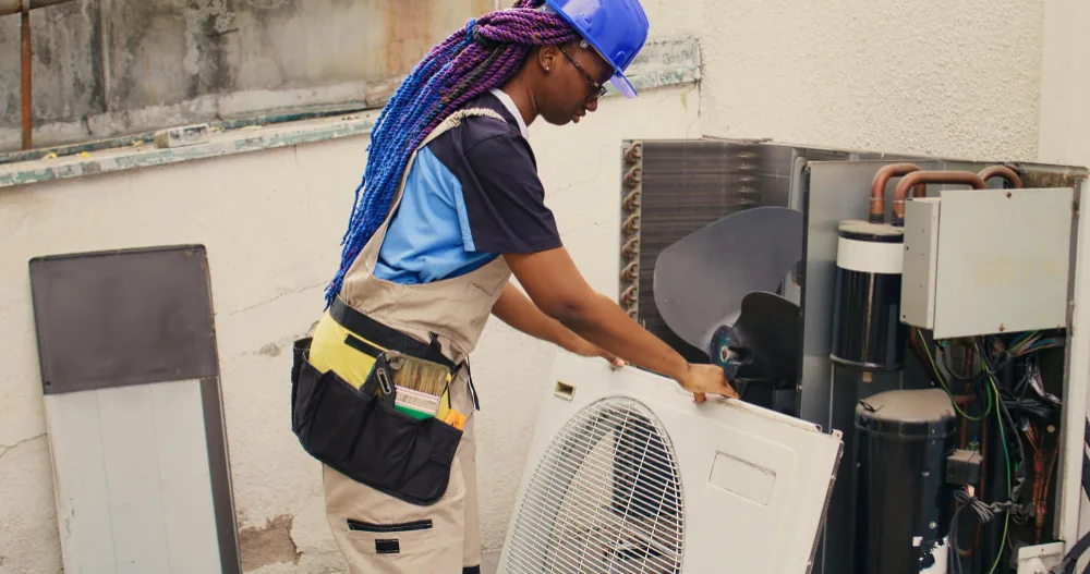 Technician performing routine maintenance on an outdoor AC unit